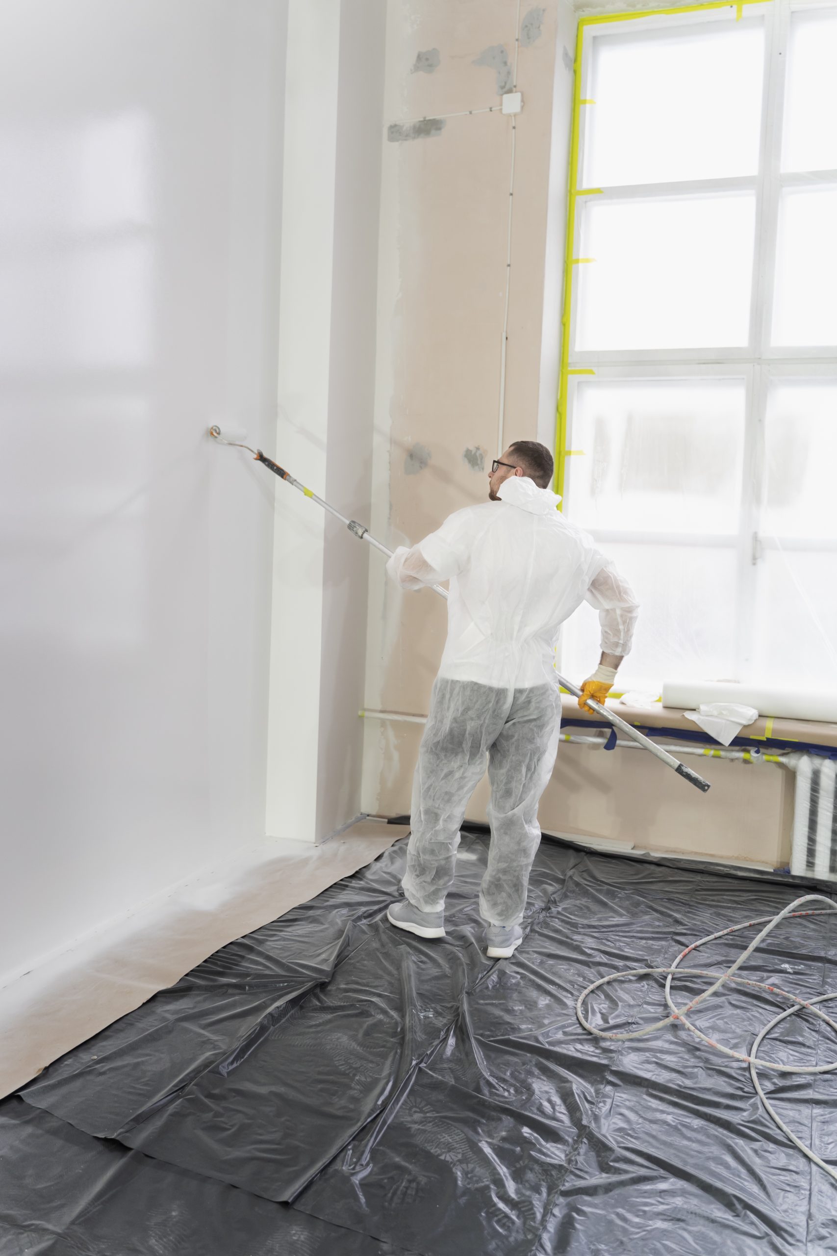 joven-trabajador-pintando-pared-tiro-completo